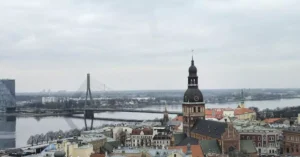 Aerial view of Riga featuring St. Peter's Church and Vanšu Bridge over the Daugava River.