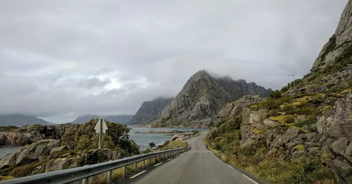 Discover Norway's breathtaking landscapes with this scenic mountain road view under a cloudy sky.