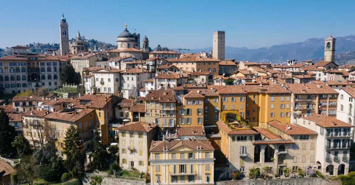 A scenic aerial view of Bergamo, Italy featuring historic buildings and landmarks under a clear blue sky.