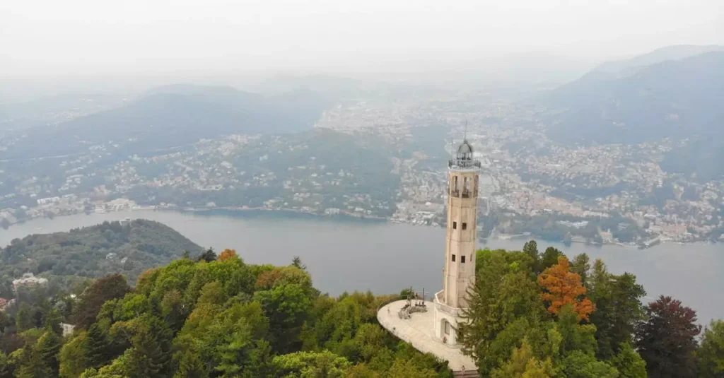 Best Northern Italy Itinerary: Dolomites to Lakes in 10 Days 2 Stunning drone footage of Brunate's lighthouse overlooking Lake Como, surrounded by lush greenery.