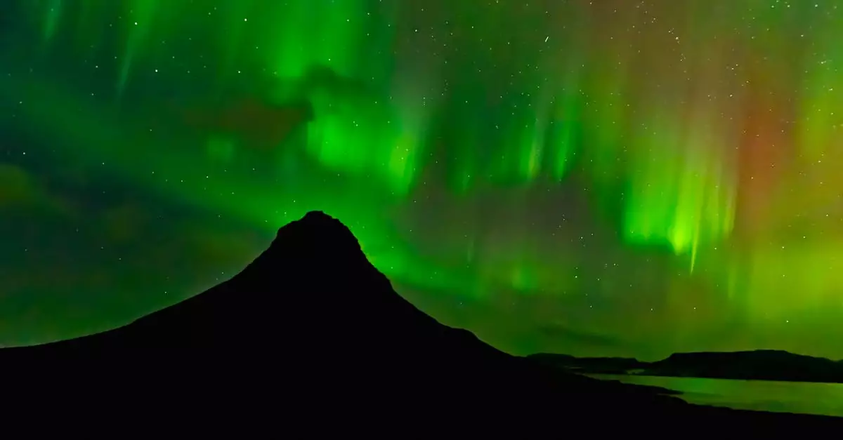 Stunning display of Northern Lights over Kirkjufell Mountain, Iceland, under starry night sky.