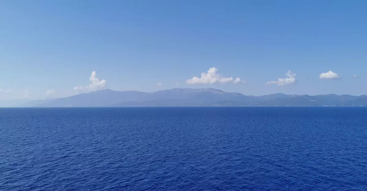 Expansive view of the Mediterranean Sea with distant mountain range under a clear blue sky.