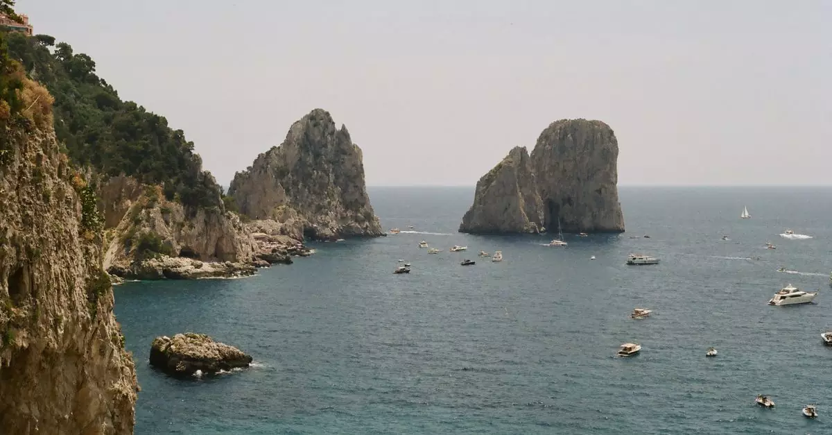 Stunning view of Faraglioni rocks off Capri, Italy with boats dotting the blue sea.