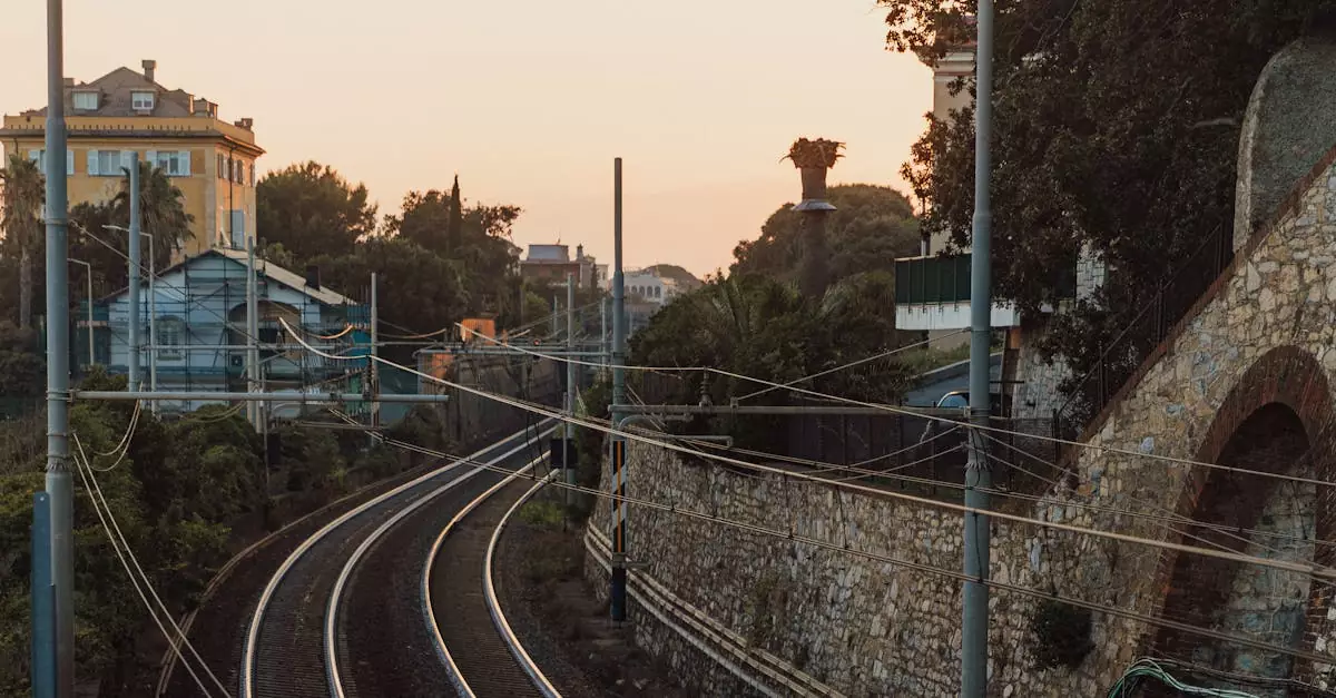 Curved railway tracks pass through a residential area with sunset hues, enhancing the scenic view.