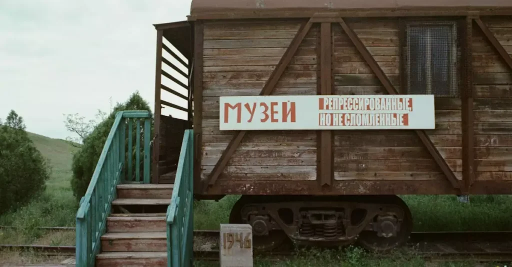 A rustic wooden train car on display in an outdoor museum setting, suggesting historical significance.