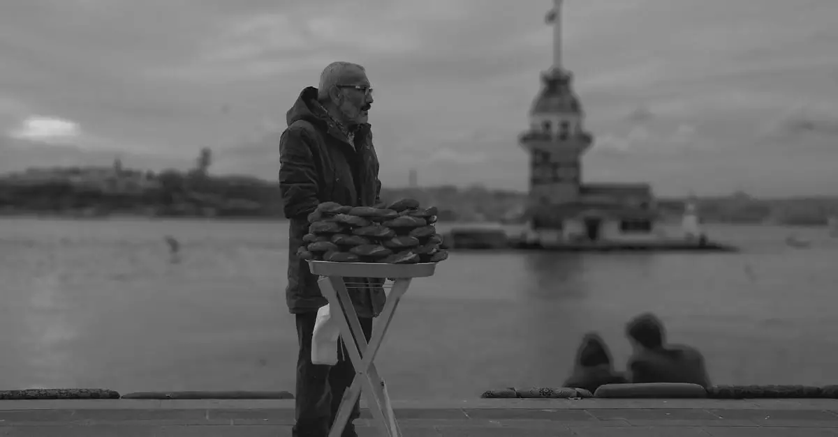 Elderly man selling pastries beside Istanbul's Maiden's Tower in grayscale.