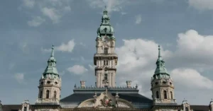 An elegant baroque tower set against a bright sky in Hungary, showcasing architectural beauty.