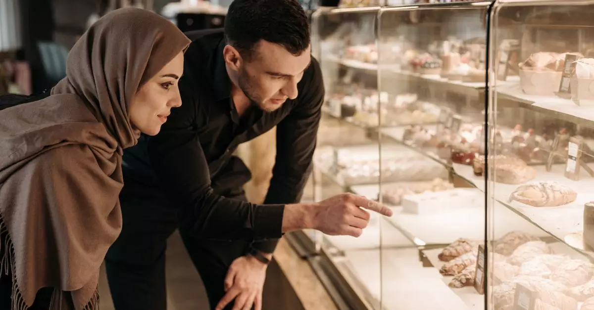 A couple selecting pastries at a bakery display case, highlighting their choice in a modern shop setting.