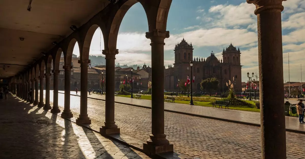 Dramatic shadows cast by colonnades in Cusco, Peru, framing a historic cathedral.