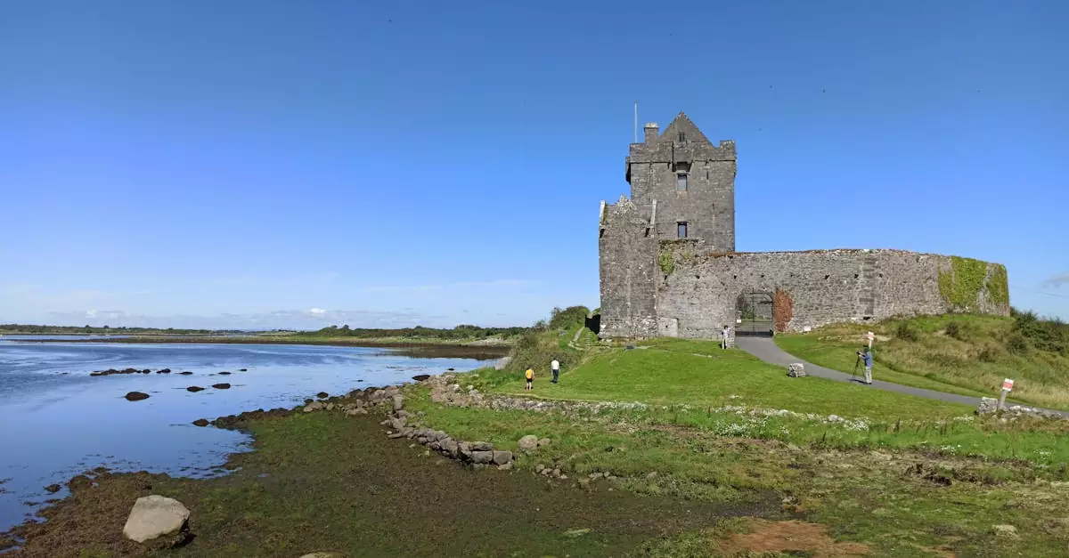 Scenic view of medieval Dunguaire Castle by Galway Bay, Ireland under a clear blue sky.