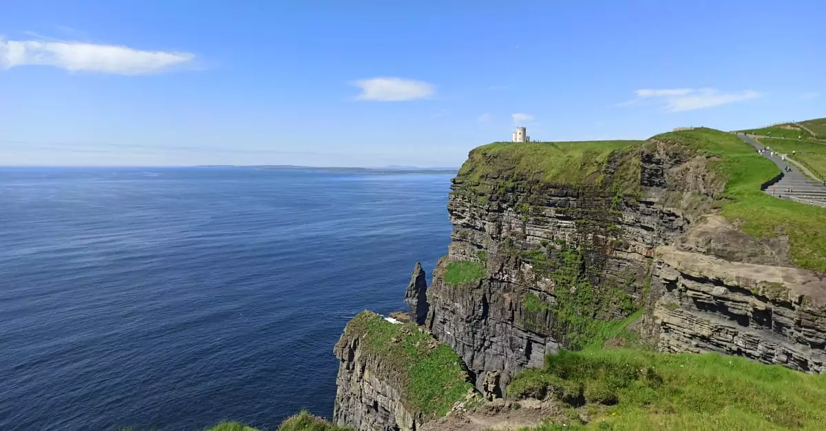 A breathtaking view of the Cliffs of Moher overlooking the Atlantic Ocean on a sunny day.