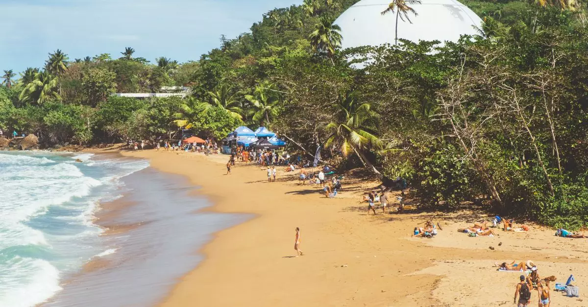 A vibrant beach scene in Rincón, Puerto Rico with people enjoying a sunny day by the sea.