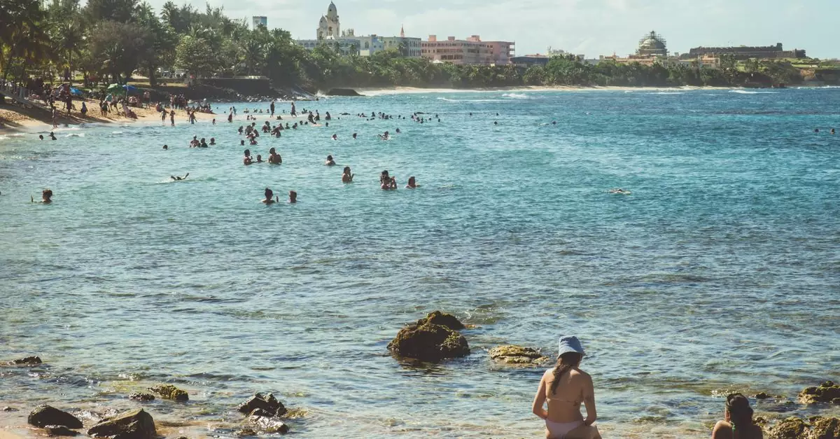 People enjoying the turquoise waters and sandy shores of San Juan's picturesque beach under a clear summer sky.
