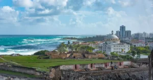 Explore the stunning view of San Juan's historic fort with ocean backdrop under a vibrant sky.