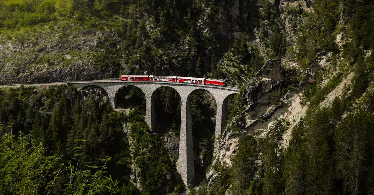 Red passenger train traveling on a stone viaduct, surrounded by lush green alpine scenery.