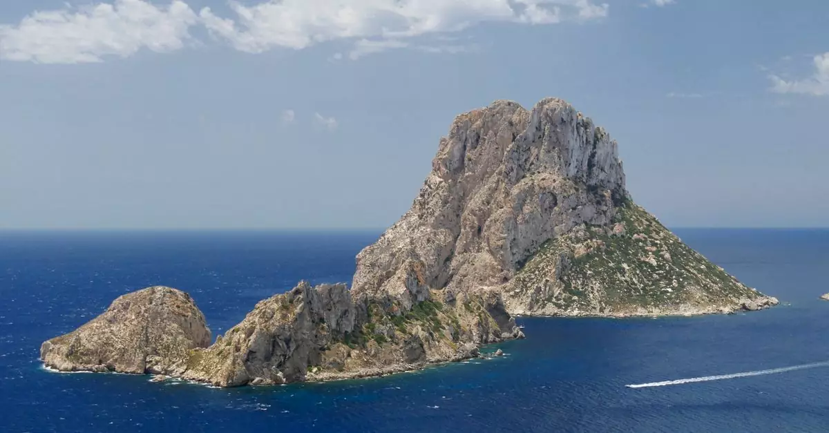 Stunning aerial view of Es Vedr&agrave; island surrounded by the Mediterranean Sea under a clear blue sky.