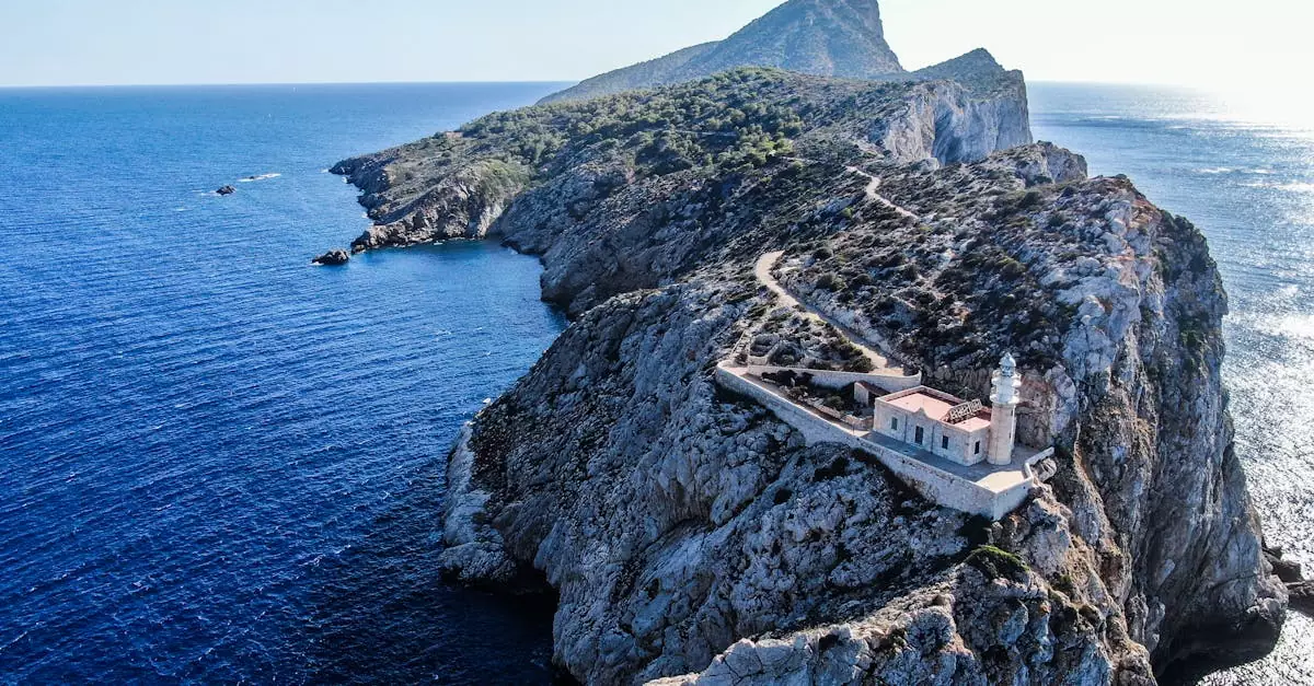 Stunning aerial photo of Punta Grossa Lighthouse on a rocky cliff surrounded by the deep blue ocean.