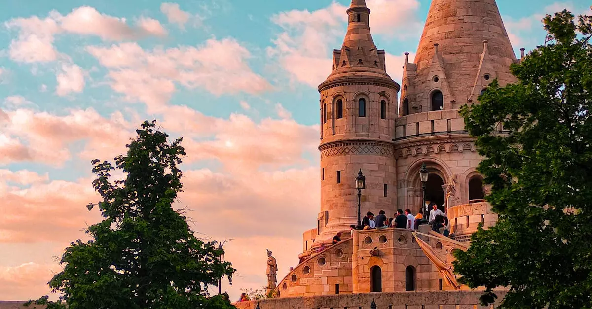 Stunning view of Fisherman's Bastion in Budapest with vibrant sunset sky and people exploring the landmark.