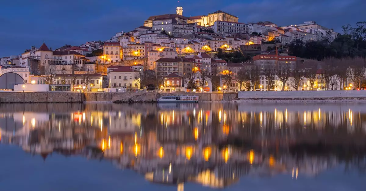 Magical evening view of Coimbra city lights reflecting in the water under a twilight sky.