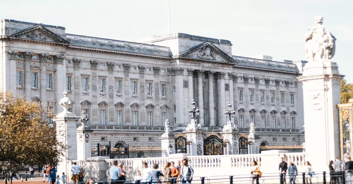 View of Buckingham Palace's facade with visitors in the foreground on a sunny day in London.