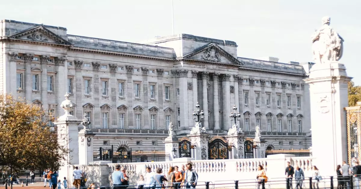 View of Buckingham Palace's facade with visitors in the foreground on a sunny day in London.