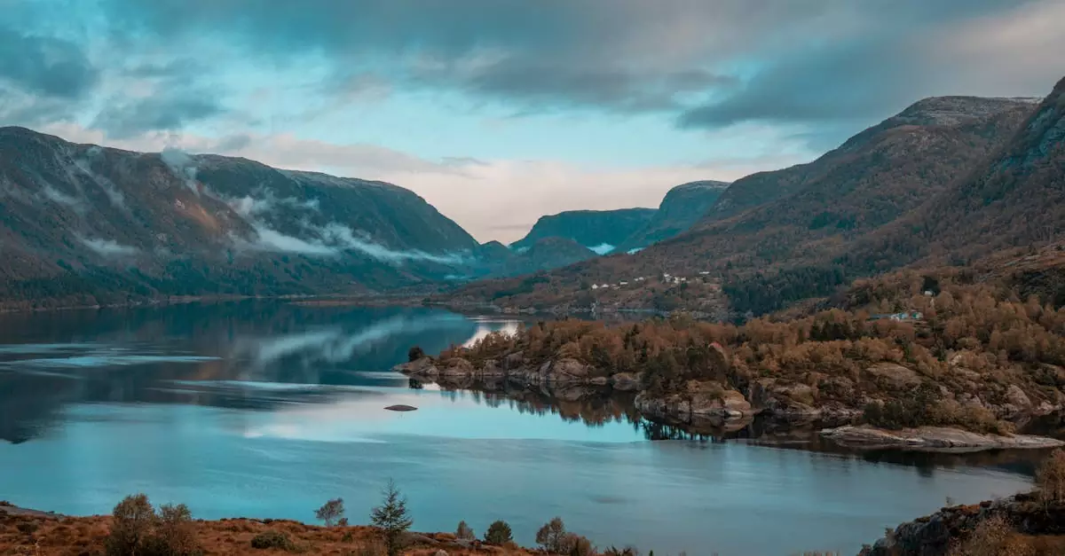 Breathtaking view of a tranquil mountain lake surrounded by lush hills and cloudy sky in Norway.