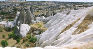 Explore the stunning rock formations and unique terrain of Cappadocia under a blue sky.