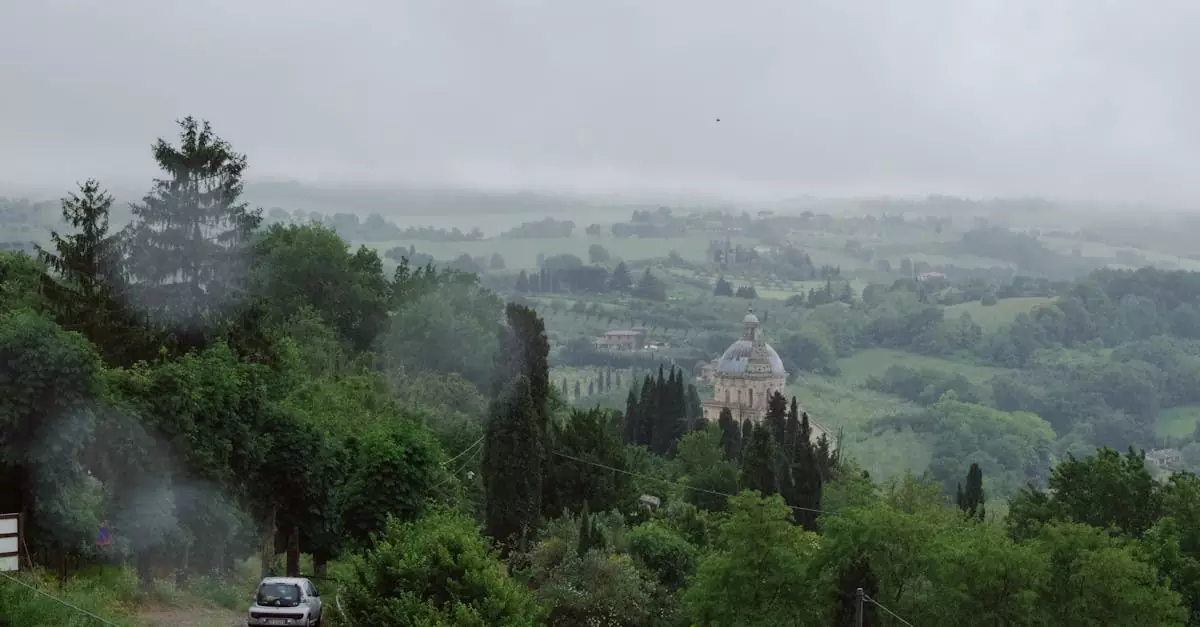 A misty landscape with Santa Maria della Consolazione in Todi, Italy amidst lush green hills and trees.