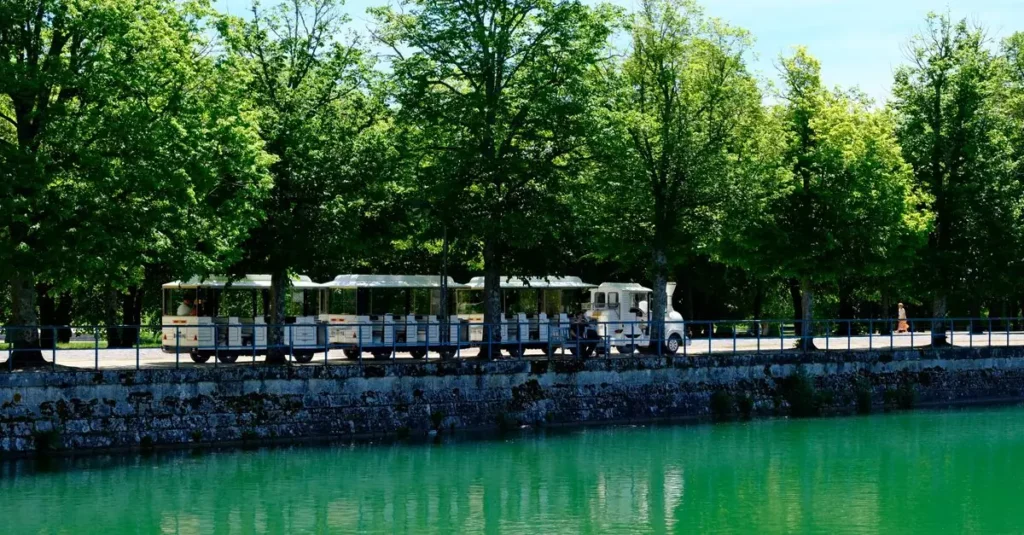 Charming tourist train alongside the serene canal in Fontainebleau, France.