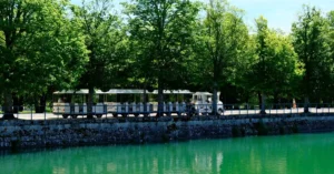 Charming tourist train alongside the serene canal in Fontainebleau, France.