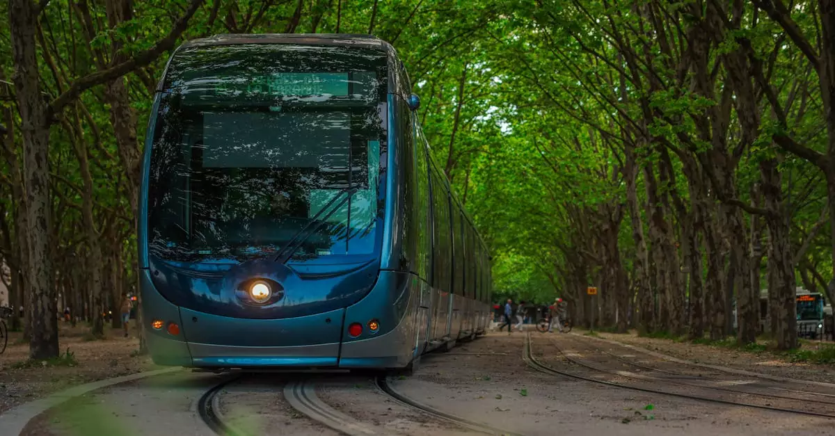 A sleek blue tram travels through a tree-lined avenue in Bordeaux, showcasing modern transportation.