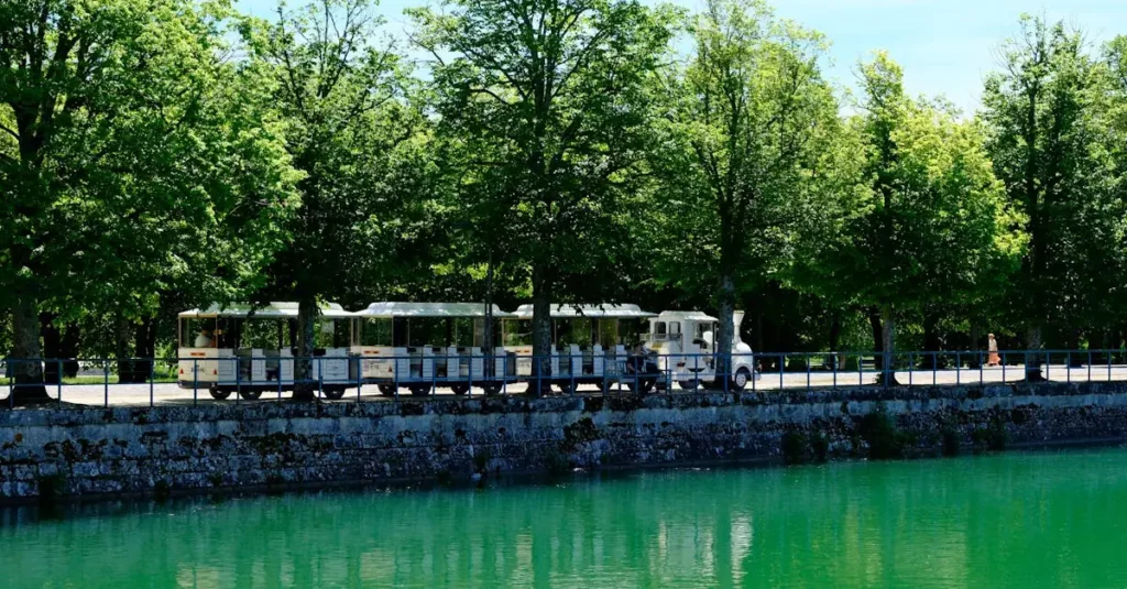Best Scenic Rail Routes France: Breathtaking Journeys 2 Charming tourist train alongside the serene canal in Fontainebleau, France.
