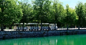 Charming tourist train alongside the serene canal in Fontainebleau, France.