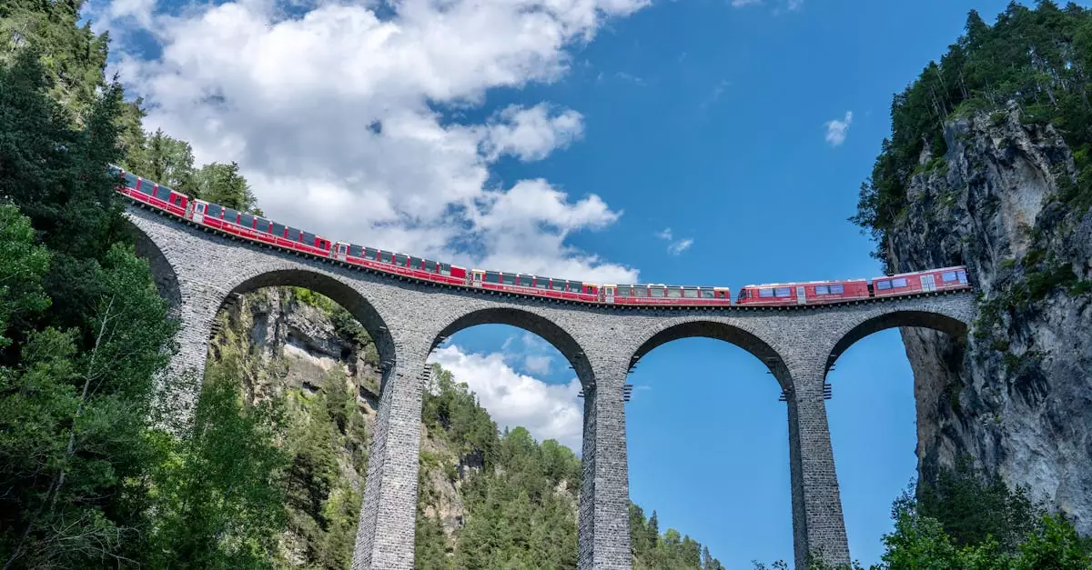 Red train crosses the iconic Landwasser Viaduct in Switzerland, surrounded by stunning alpine scenery.