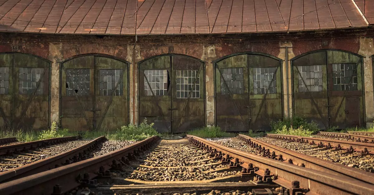 A vintage railway station with rustic, abandoned tracks leading to aged, rusted sheds.
