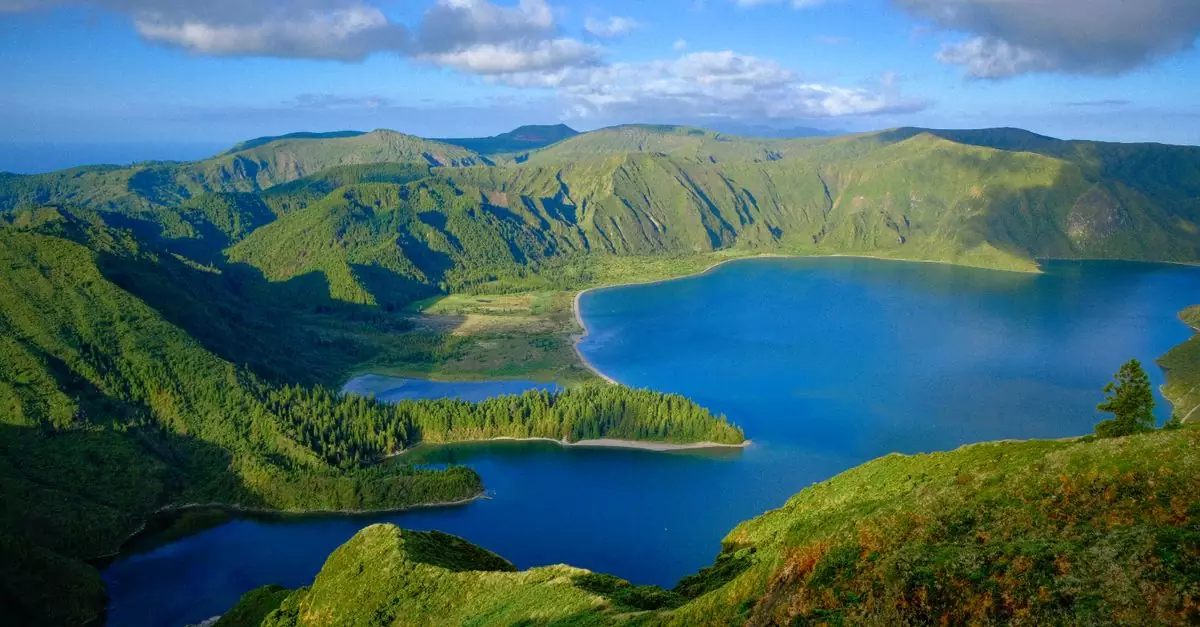 Explore the serene beauty of a lush green landscape with a tranquil lake on São Miguel Island.
