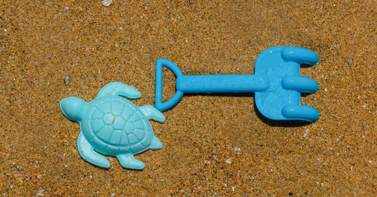 Close-up of blue plastic turtle and shovel on wet sand, perfect for beach-themed content.
