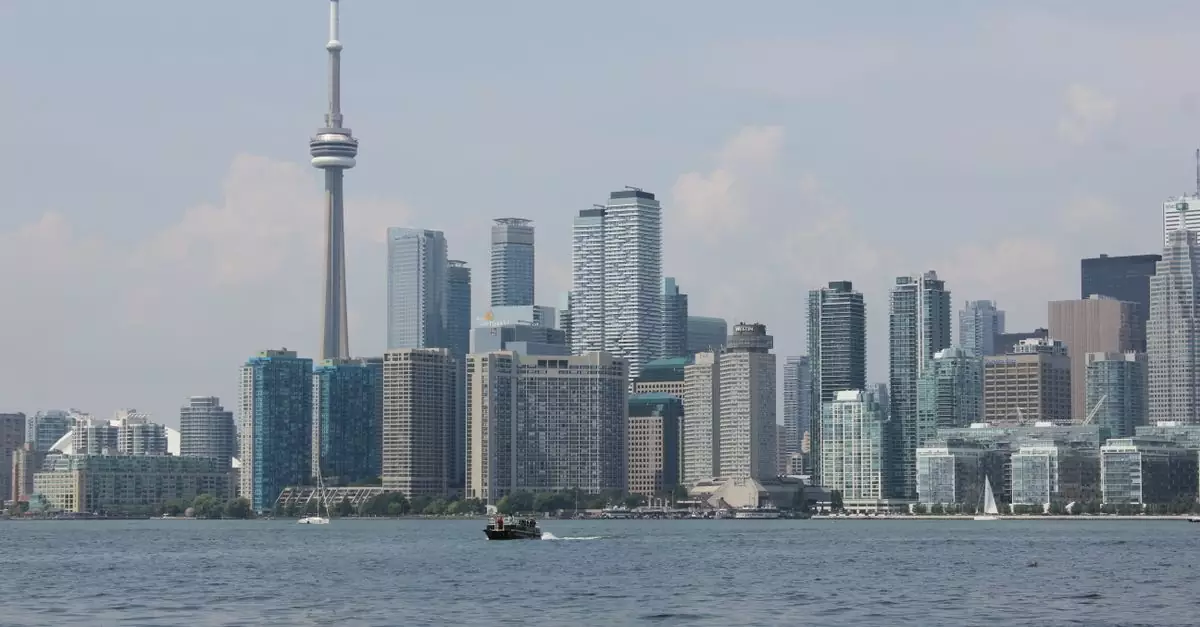 Scenic view of Toronto skyline with CN Tower over Lake Ontario under clear skies.