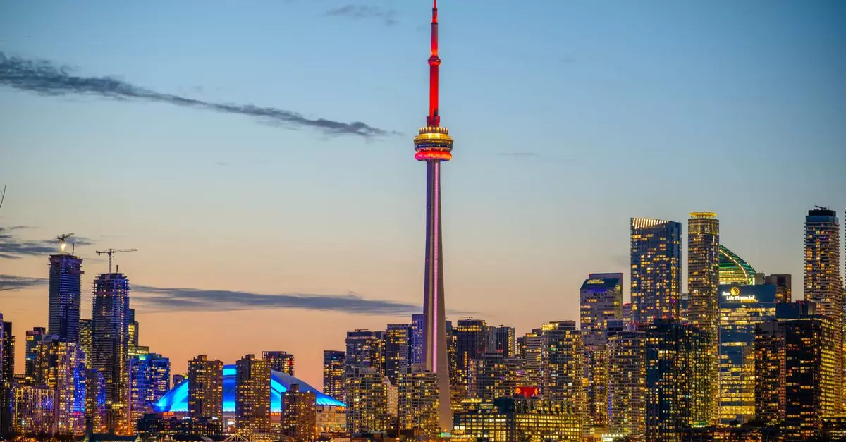 Beautiful sunset view of Toronto skyline with CN Tower and city lights reflecting on the lake.