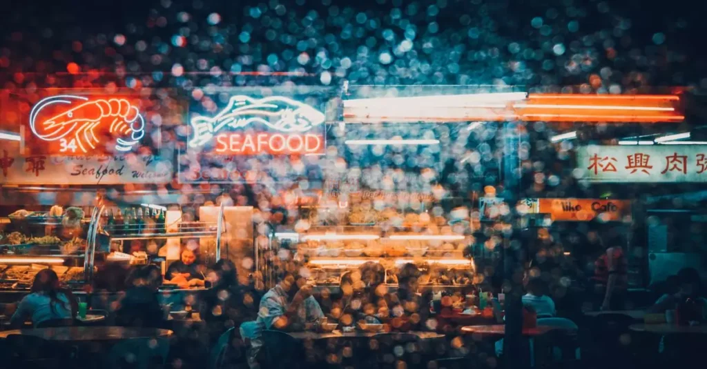 Best Seafood Destinations in South America 2 Explore the neon-lit ambiance of a bustling seafood market in Kuching at night, captured through a rain-splattered lens.