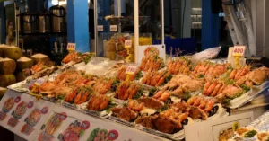 Vibrant seafood stall with prawns and fish on display in an outdoor night market setting.