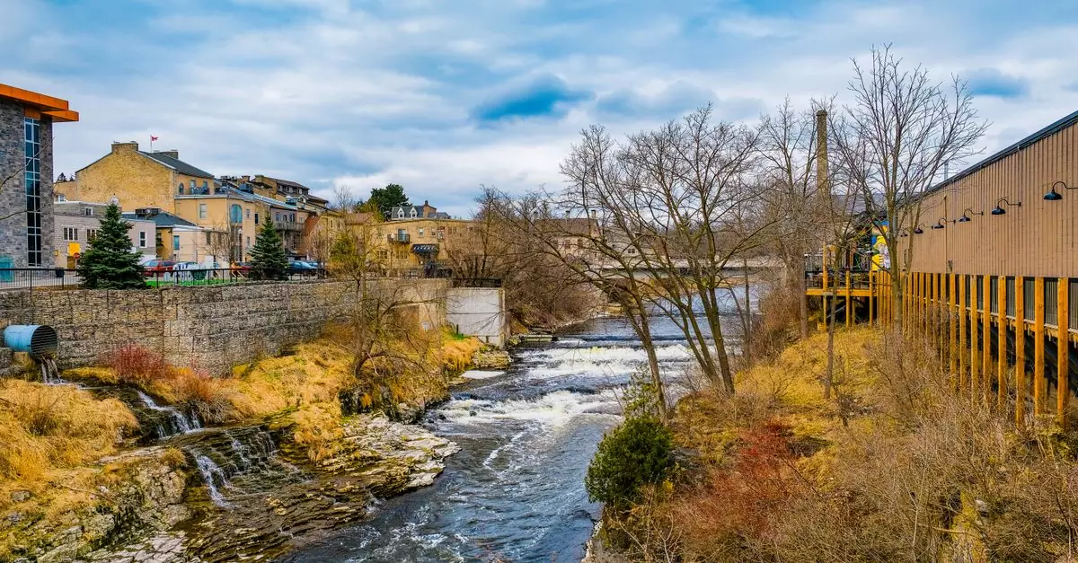 Scenic river view with historic architecture in Fergus, Ontario, highlighting nature and urban charm.