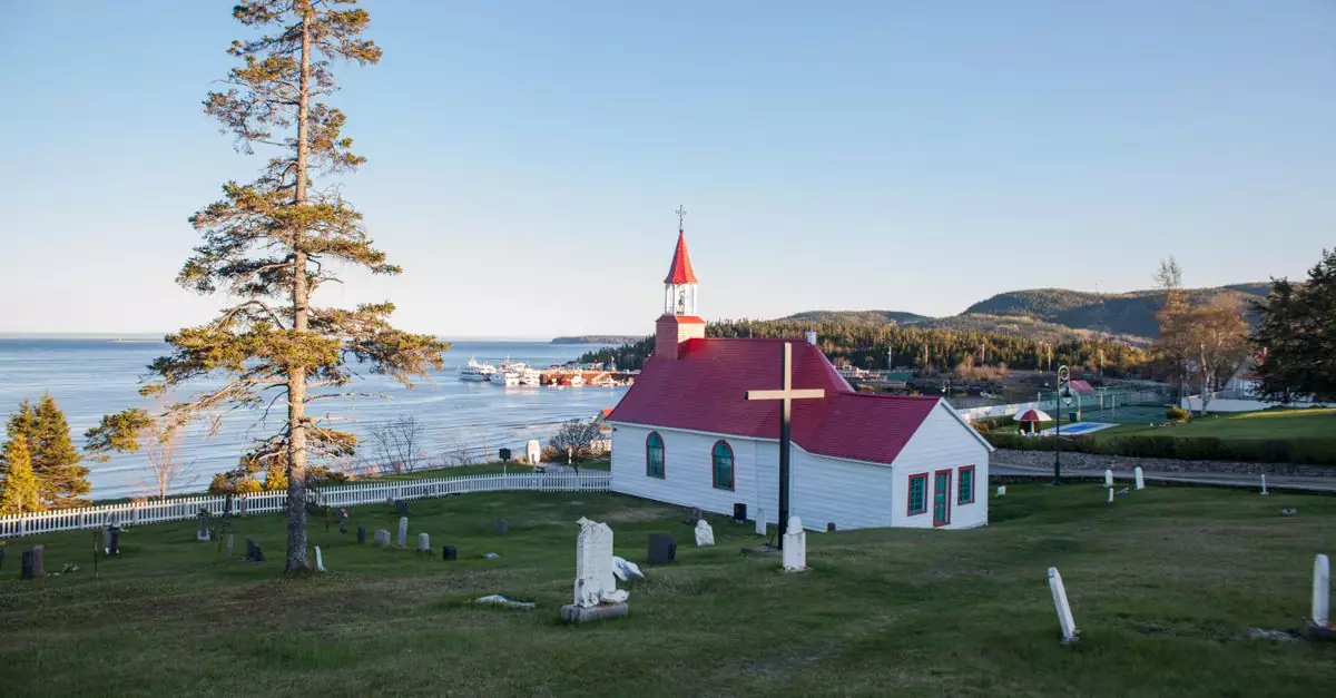 Charming church with a red roof overlooking scenic Tadoussac Bay in Québec, Canada.