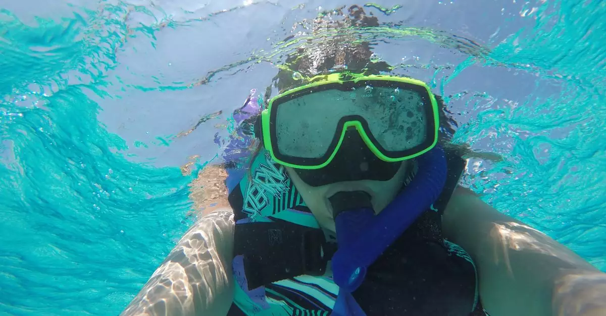 Snorkeler explores vibrant blue waters of Cayman Islands.