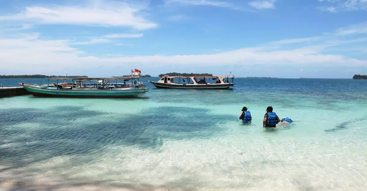 Serene beach scene in Jakarta with boats docked and people enjoying the turquoise sea.