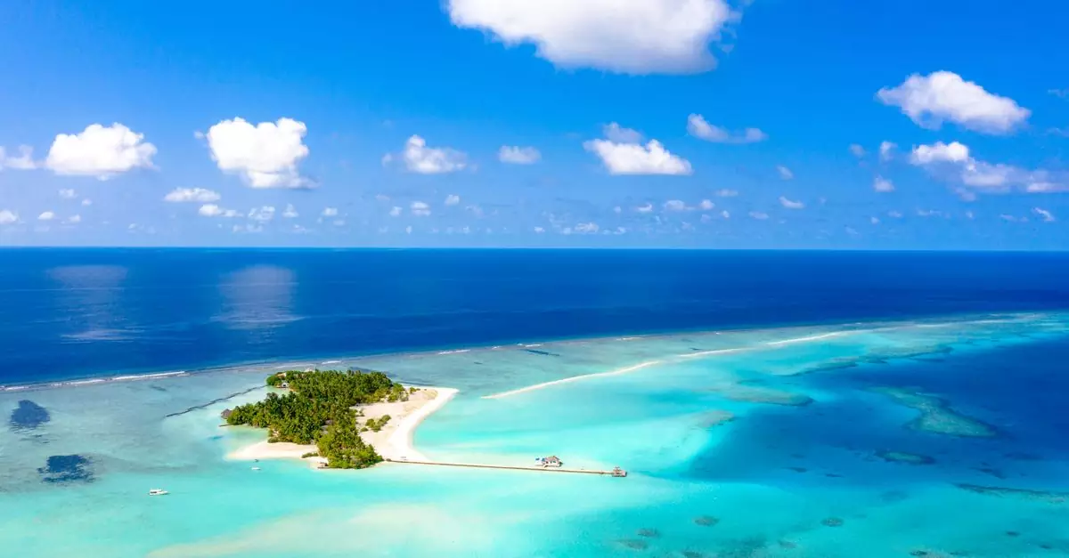 Stunning aerial view of a serene tropical island surrounded by turquoise waters in the Maldives.