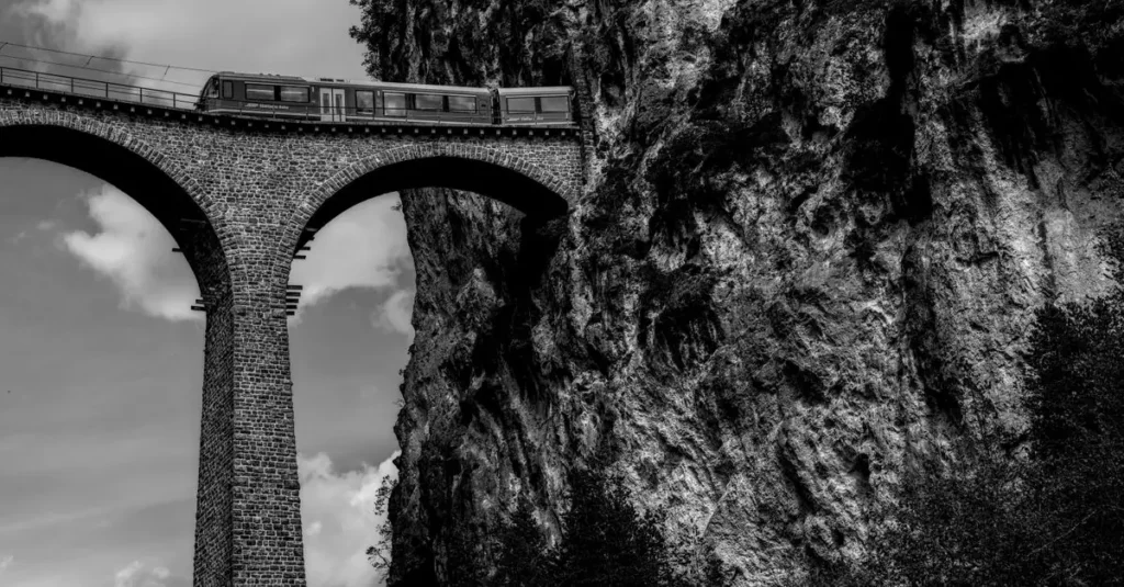 Best Train Travel Experiences in South America 2 Black and white photo of a train crossing the iconic Rhaetian Railway bridge in Switzerland.