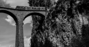 Black and white photo of a train crossing the iconic Rhaetian Railway bridge in Switzerland.