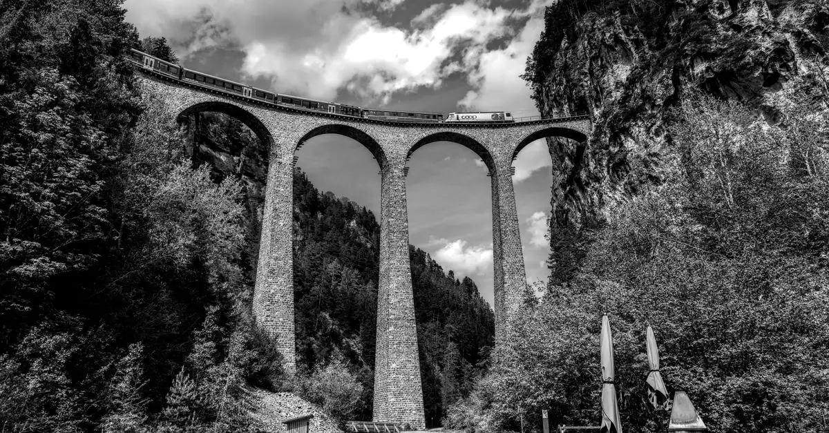 Black and white photo of Landwasser Viaduct in Switzerland with a train passing over it.