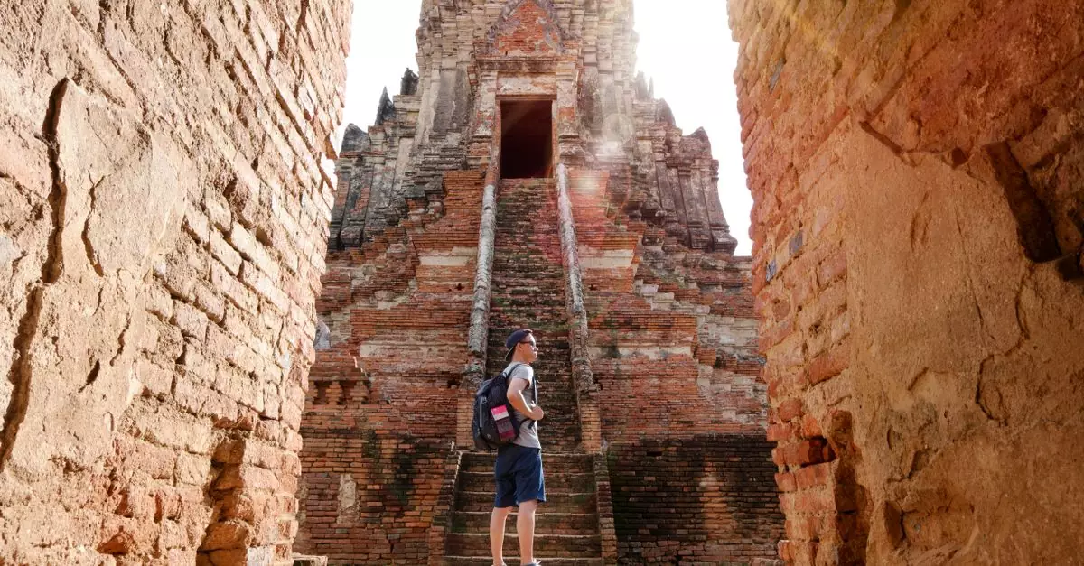 A man with a backpack sightseeing ancient brick temple in summer sunlight.
